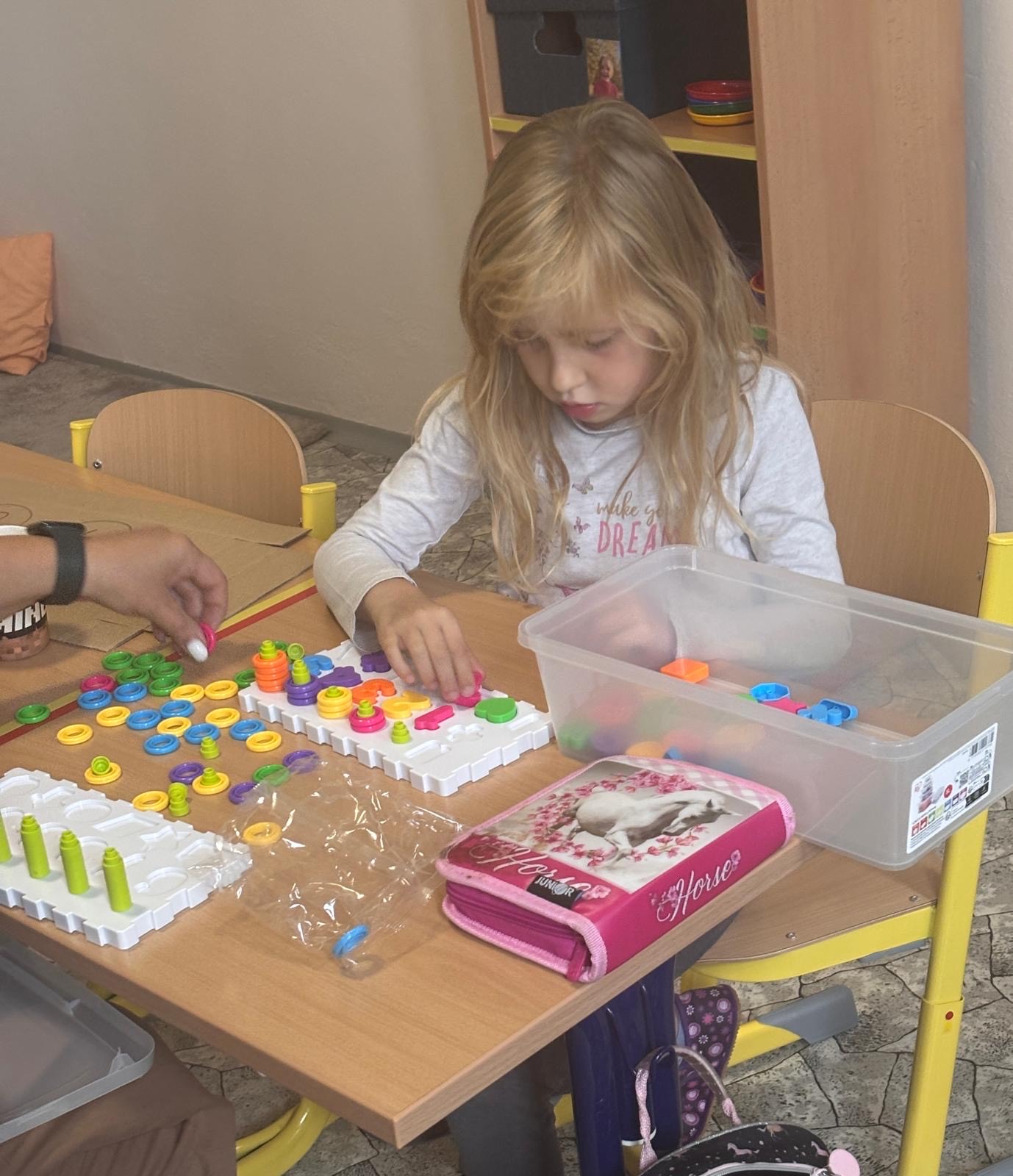 Dívka třídí barevné mozaikové knoflíky na deskách